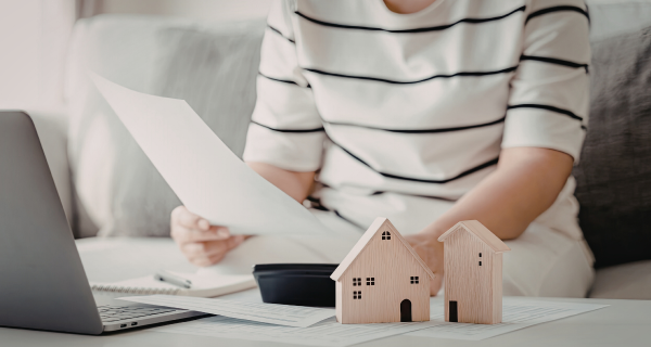 Person reviewing paperwork with small wooden house models on a desk
